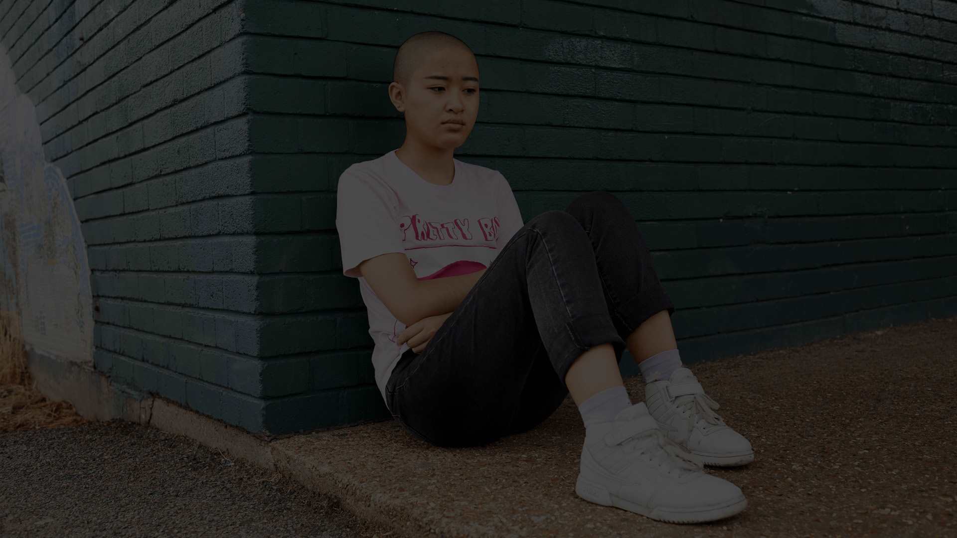 A person sitting against a brick wall