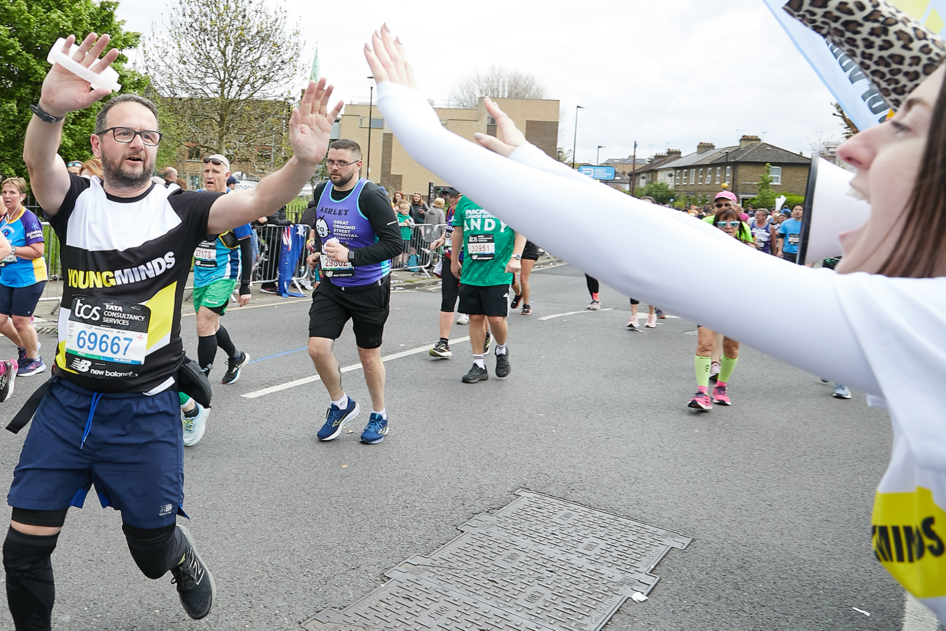 A YoungMinds marathon runner being supported by YoungMinds staff on the side line.