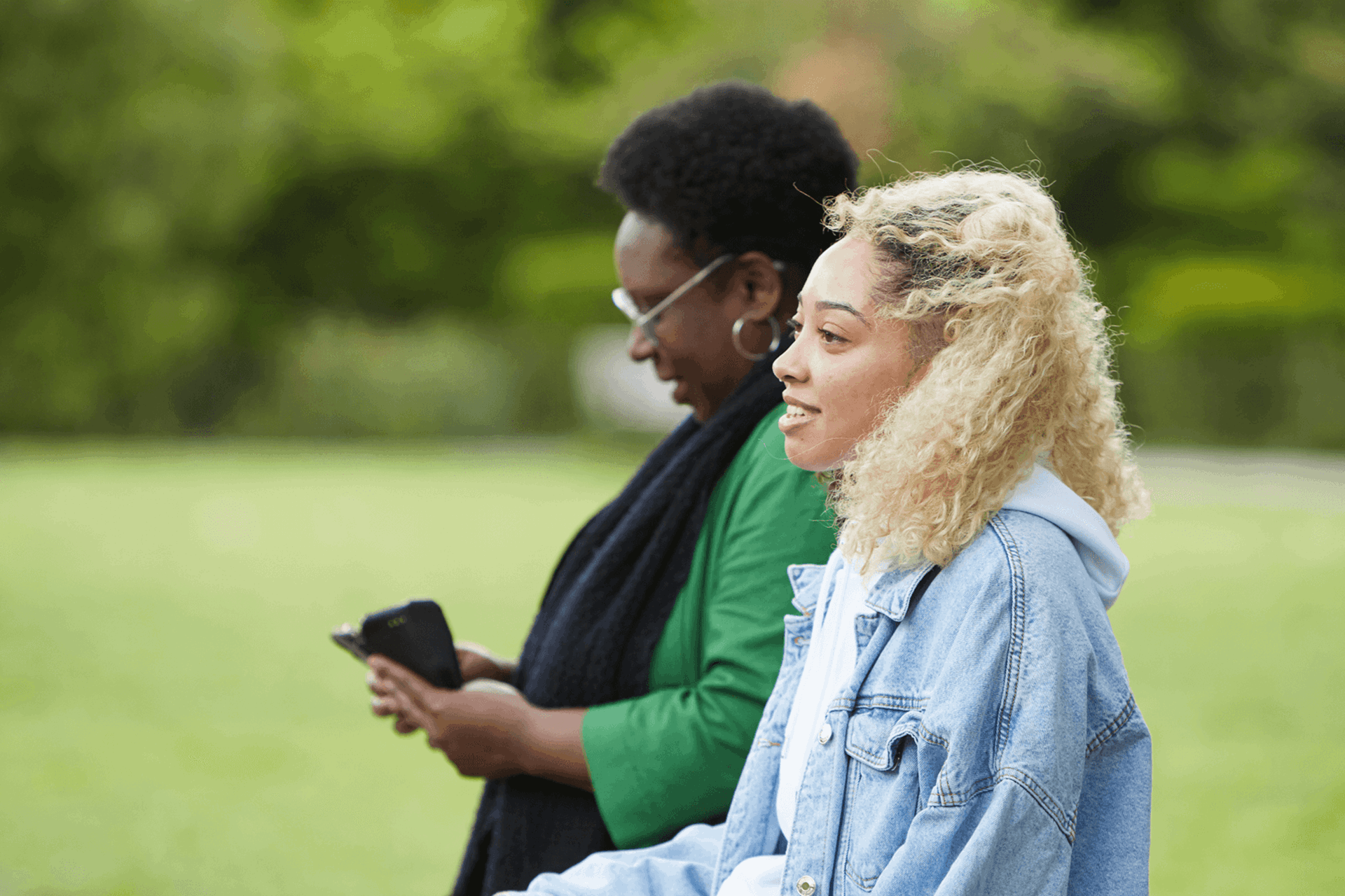 Two girls walking in the park smiling