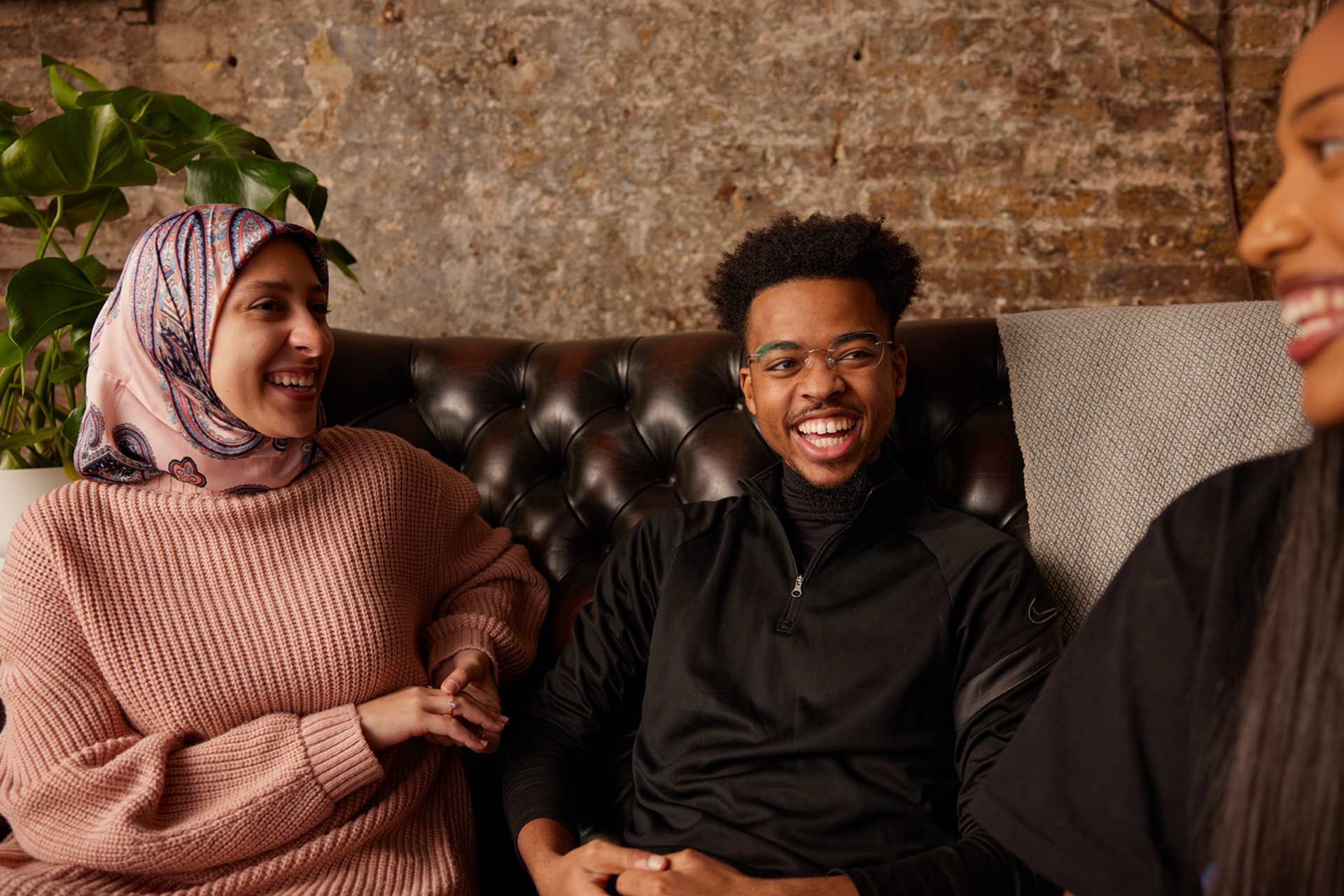 Three people sitting and laughing on the sofa.