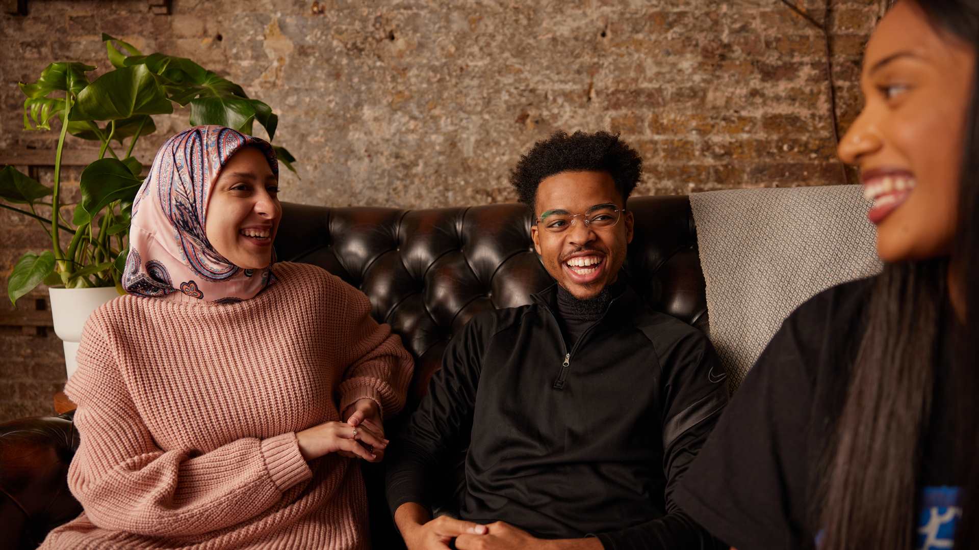 Three people sitting and laughing on the sofa.