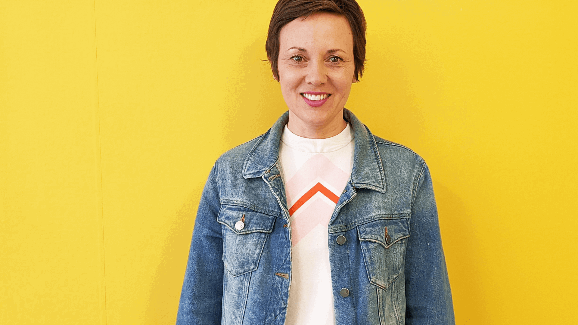 YoungMinds staff member Roxane Caplan smiling against a yellow background
