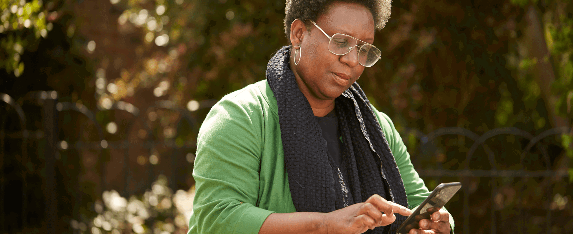 A lady typing on her phone while sitting at a picnic table