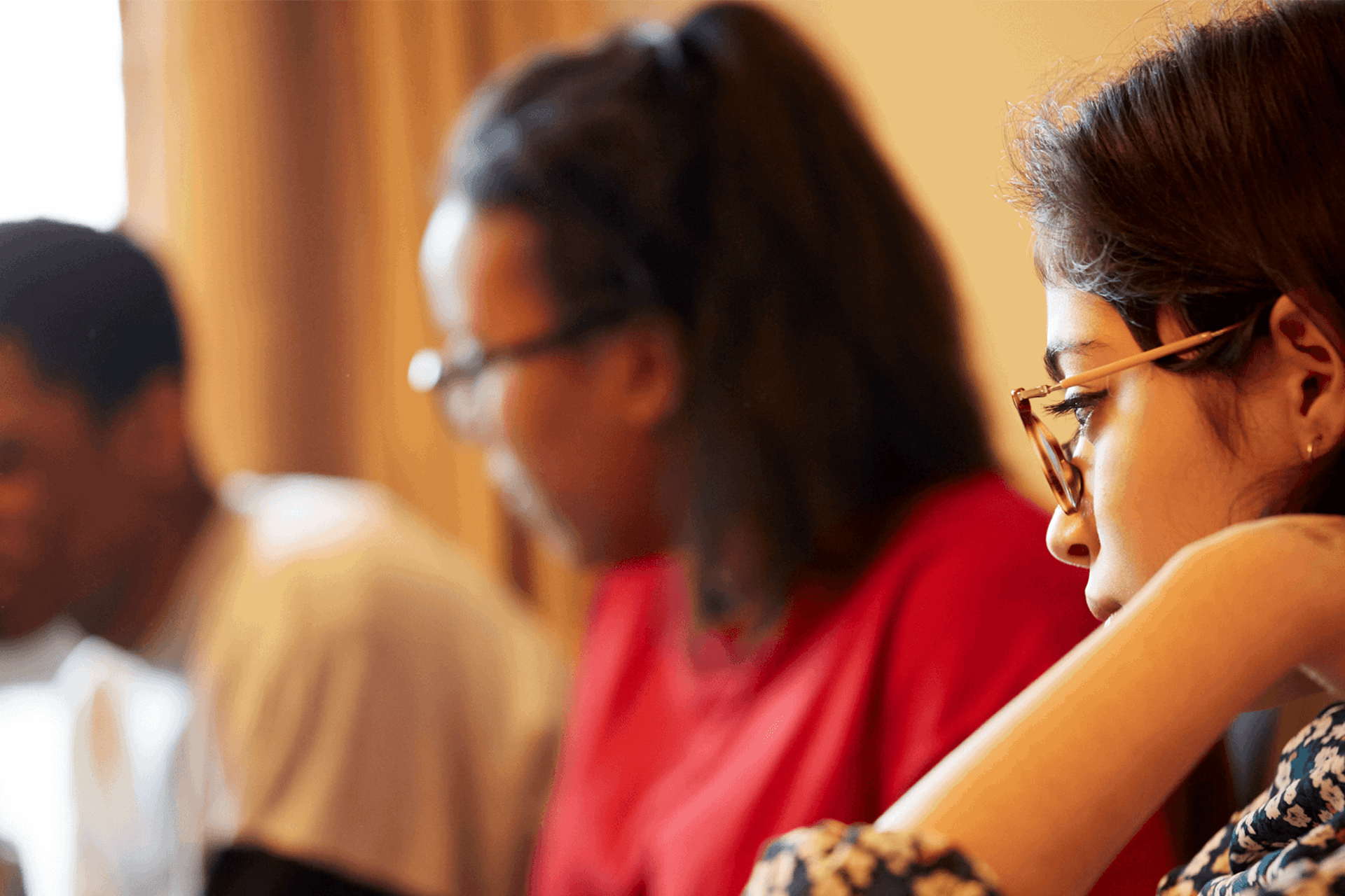Three young people sitting and talking together in a livingroom.
