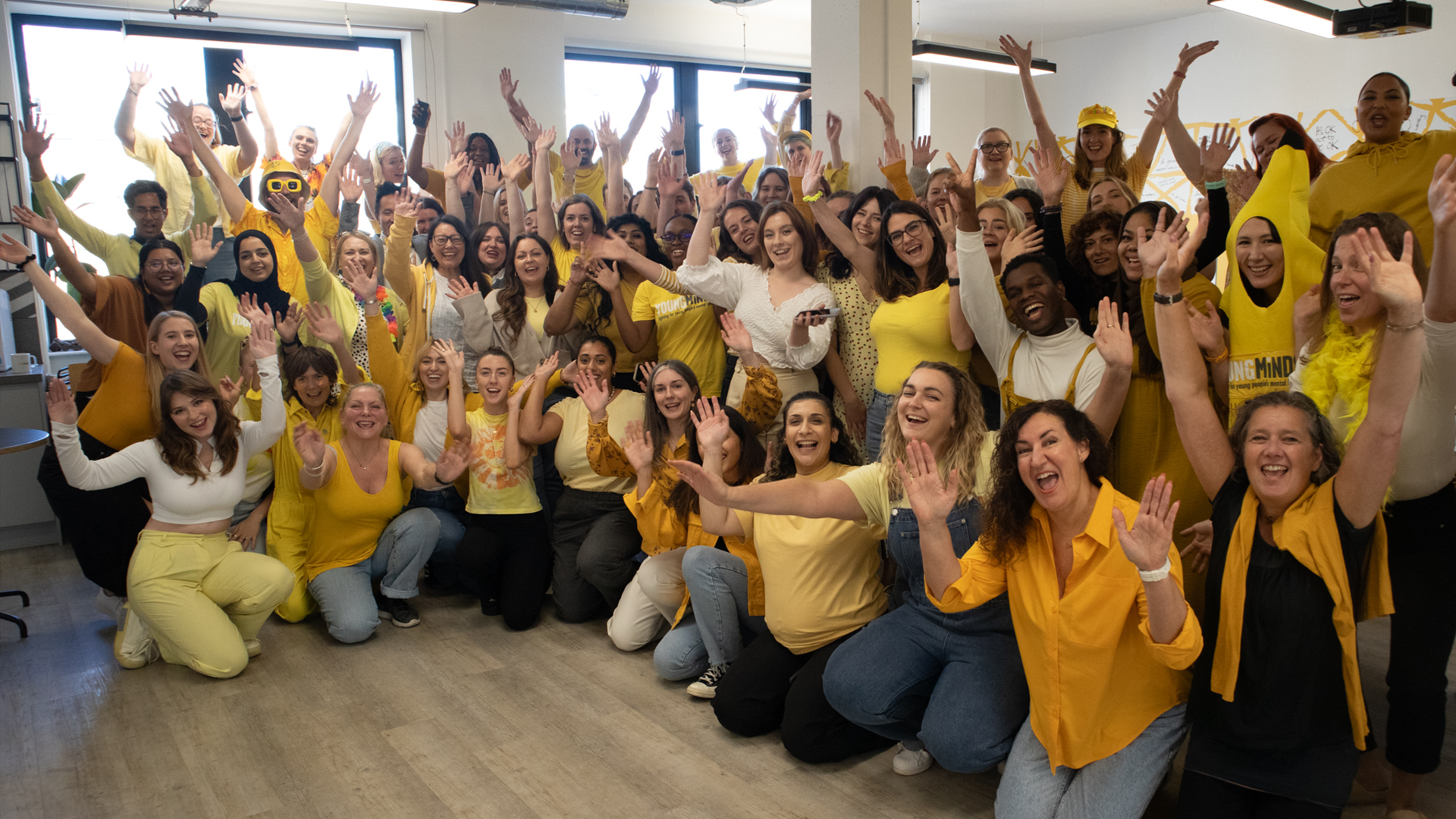 YoungMinds staff all wearing yellow for #HelloYellow 2023, posing with their hands in the air.