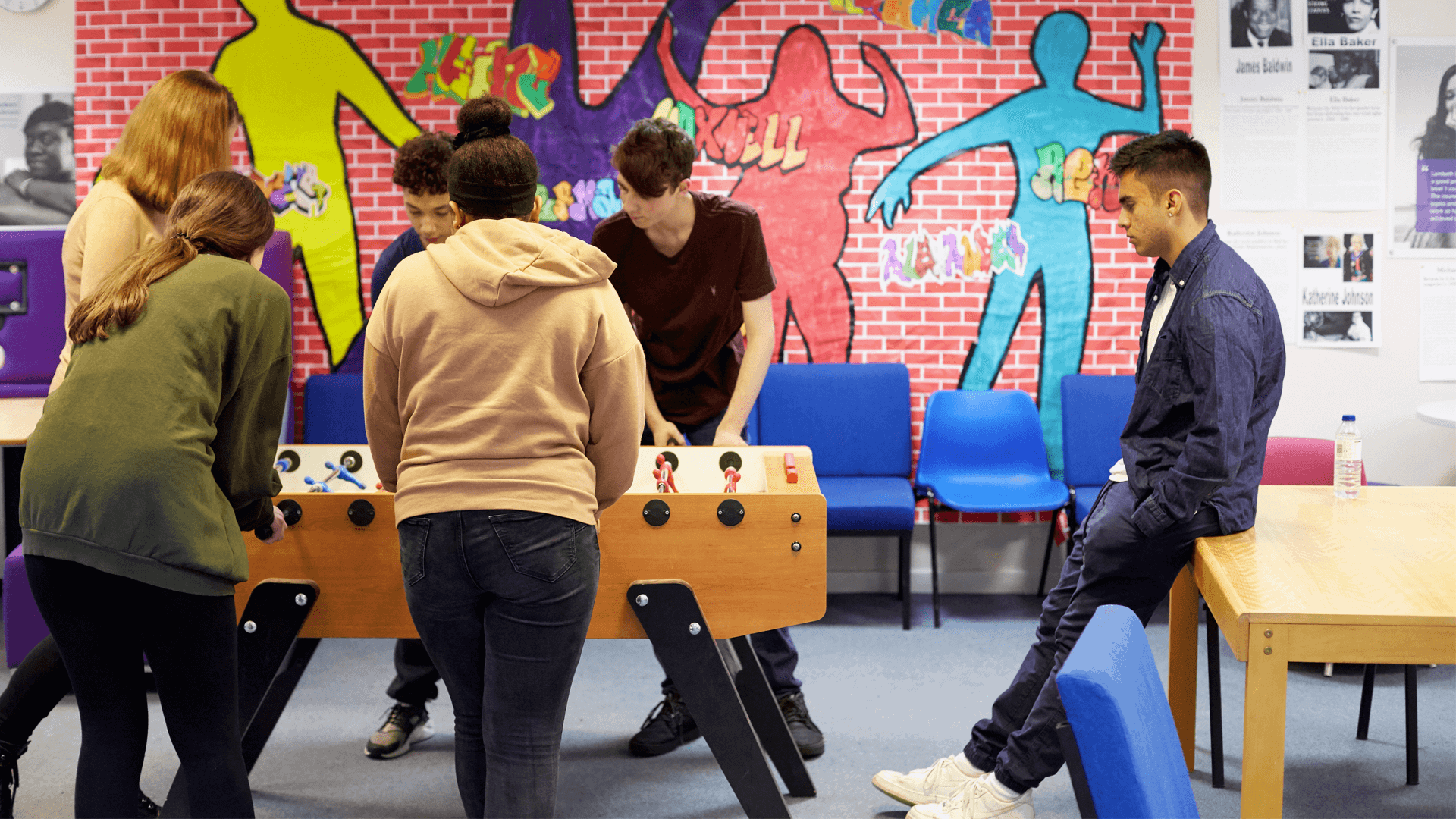 Six young people playing table football in a youth club.