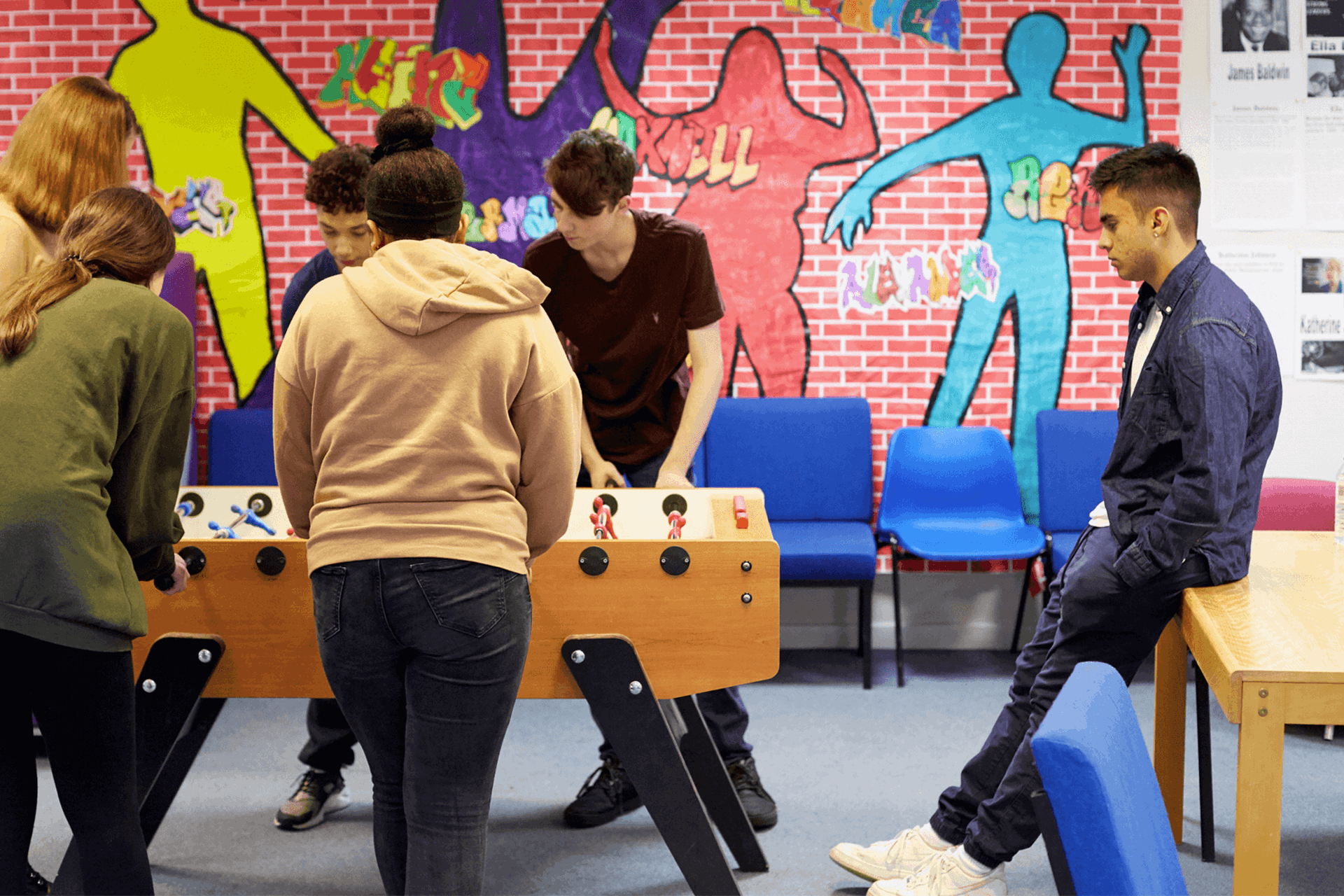 Six young people playing table football in a youth club.