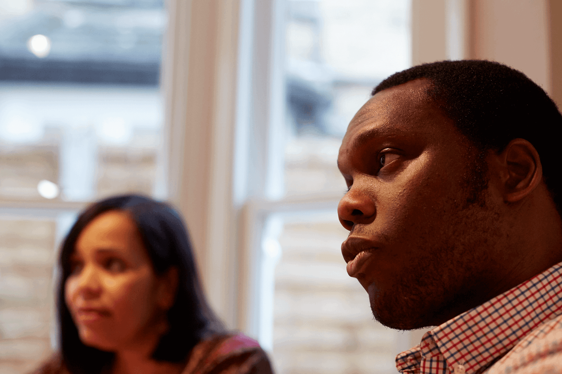 Close up of a man engaging in conversation with a lady in the background