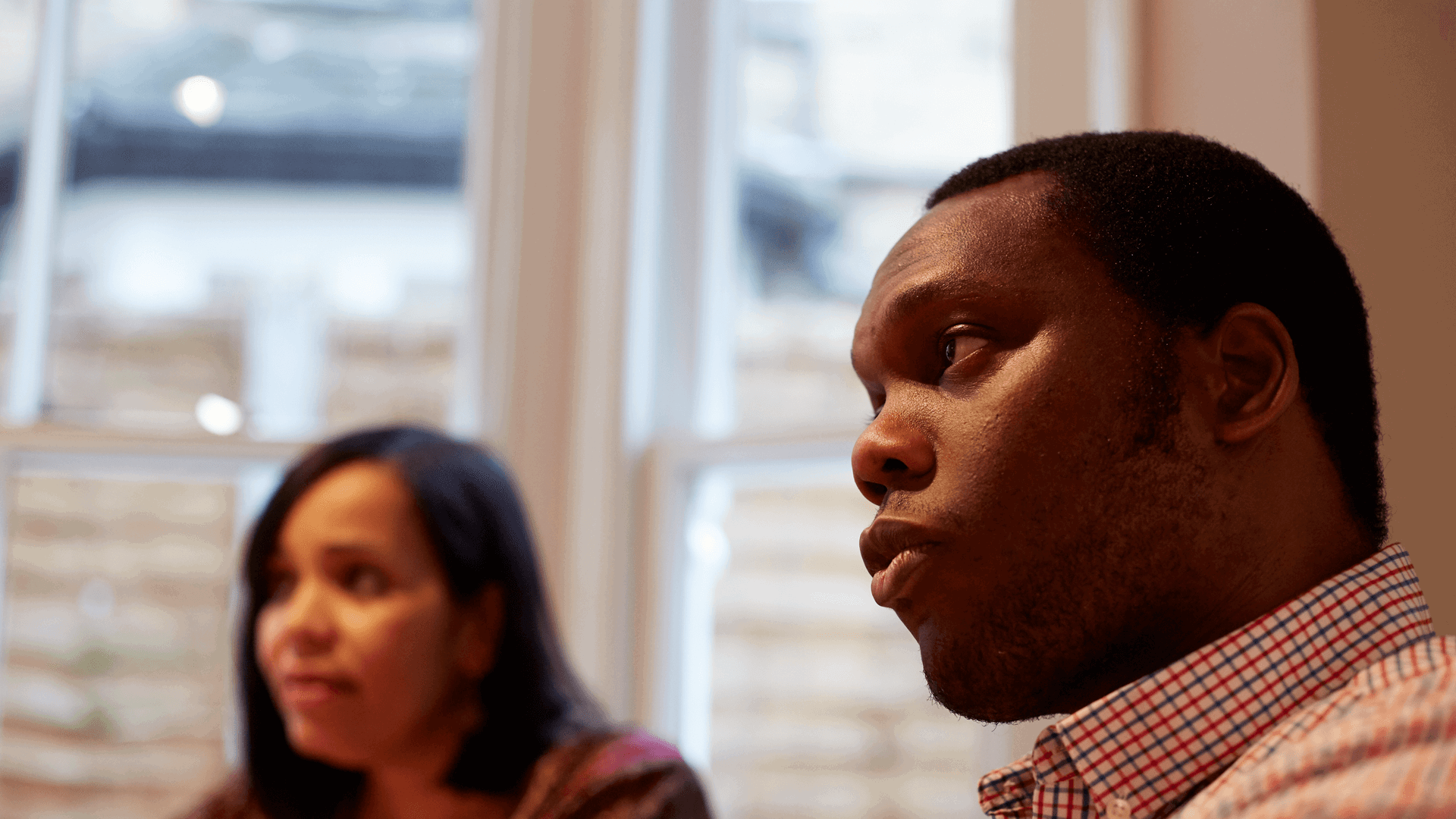 Close up of a man engaging in conversation with a lady in the background