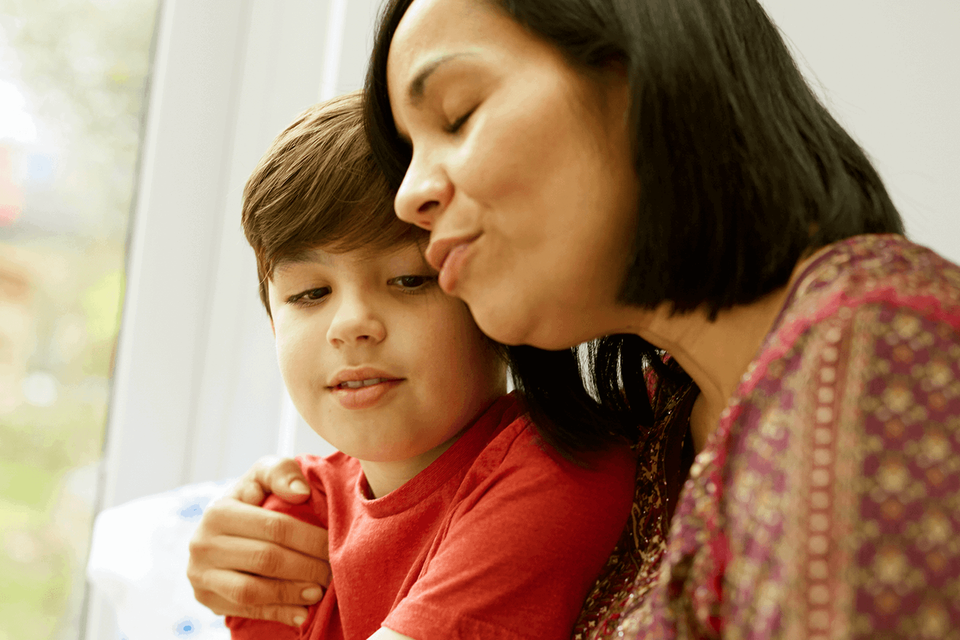 Parent talking to their son with their arm around him.