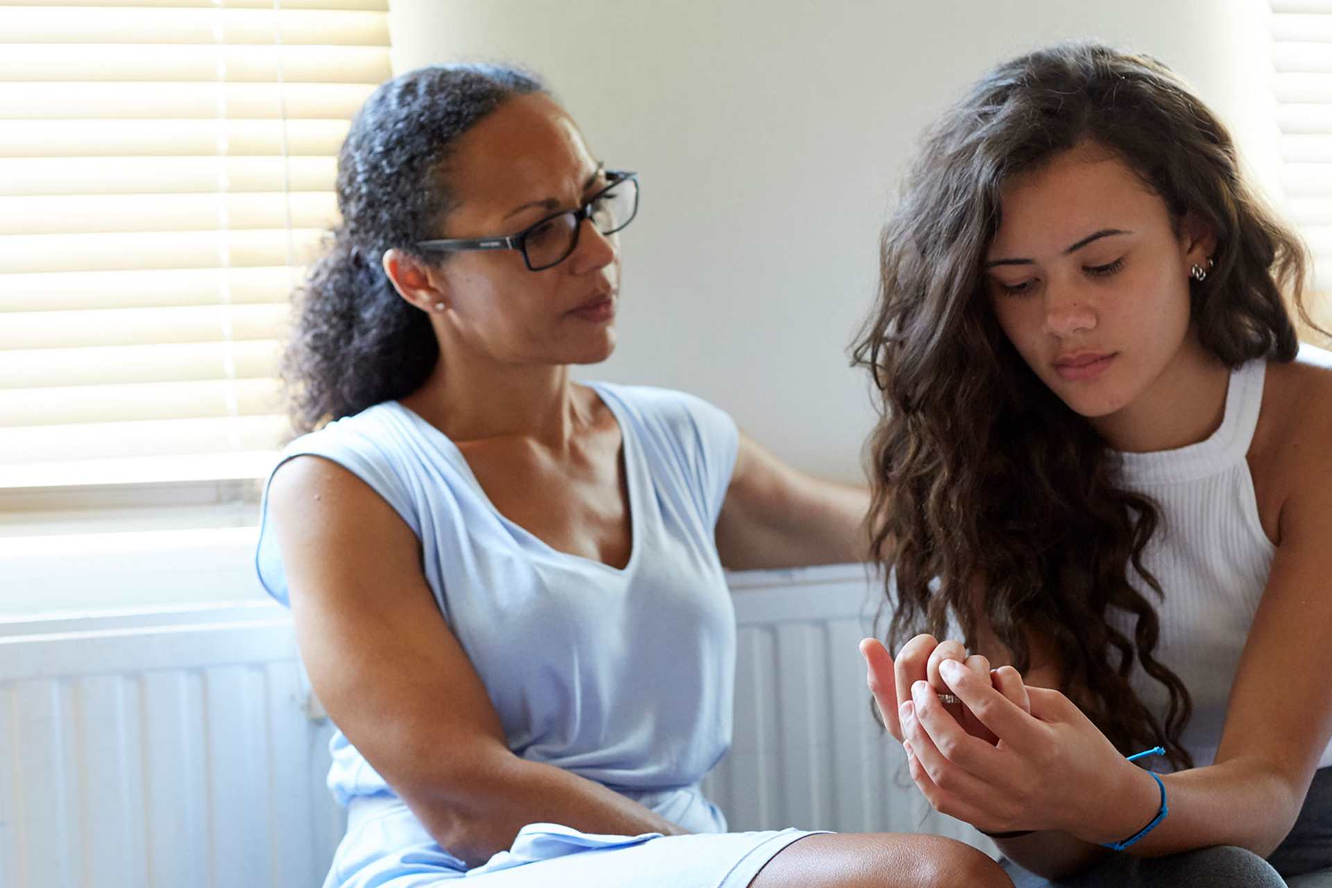 A mother and daughter having a serious discussion at home in front of a radiator