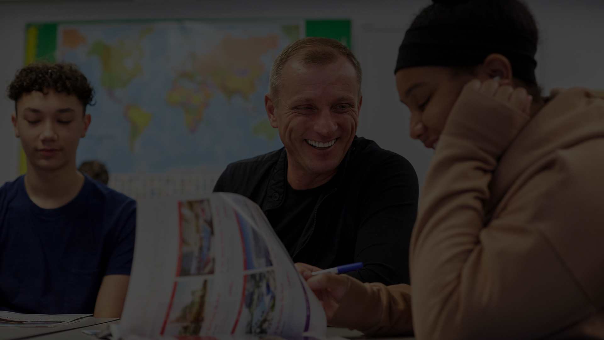 A teacher smiling with two students