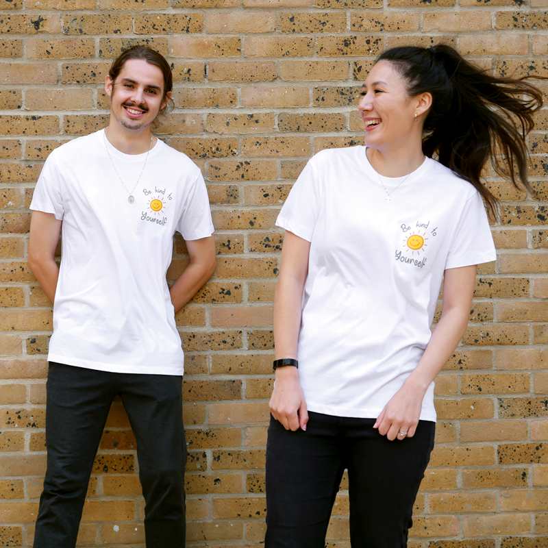 Girl and boy laughing while wearing YoungMinds shirt with Be Kind To Yourself text graphics