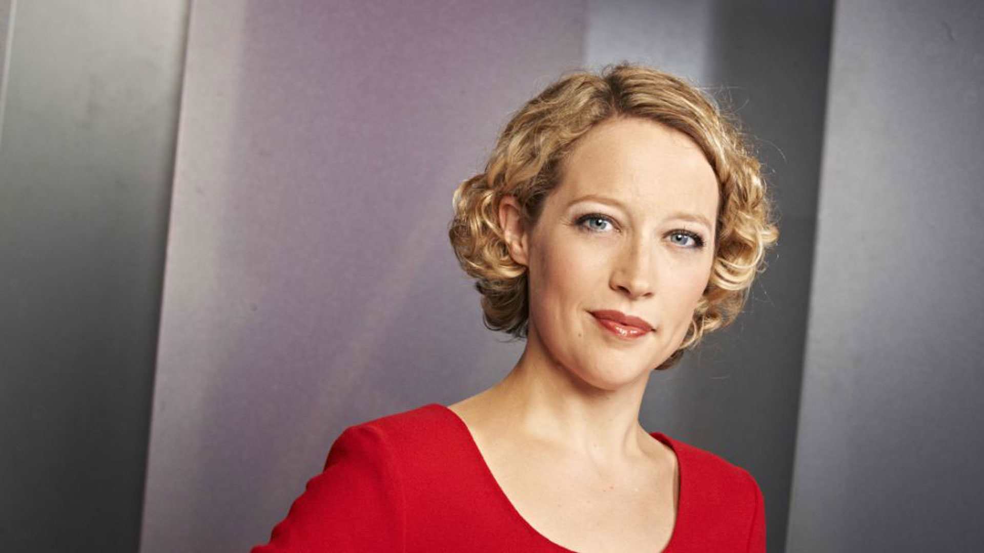 Journalist Cathy Newman in a red top in front of a grey background