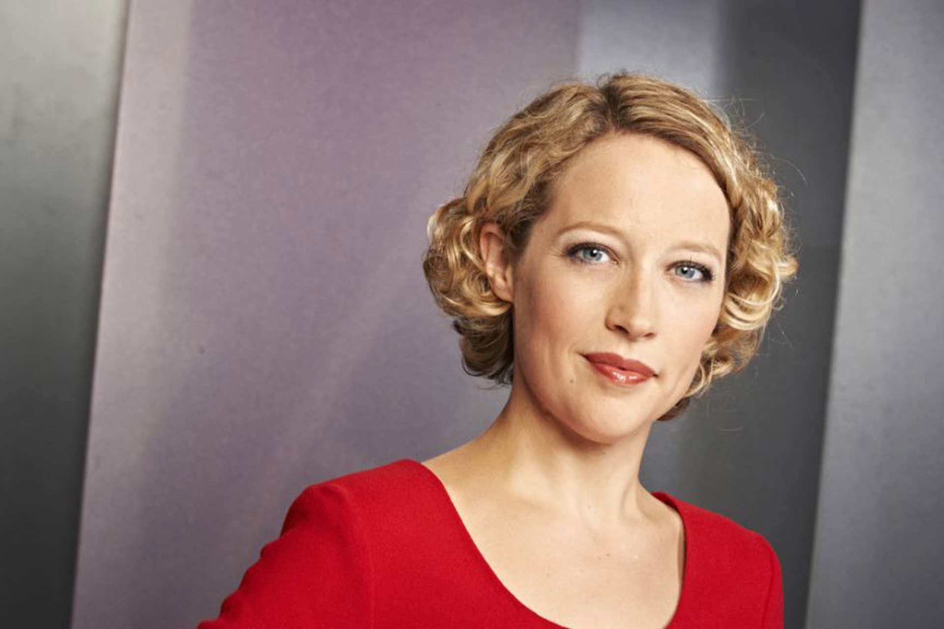 Journalist Cathy Newman in a red top in front of a grey background