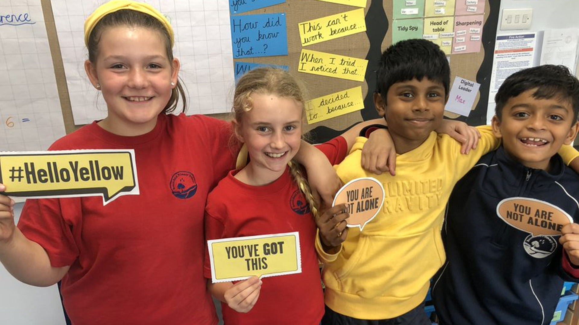 Four children from Brookfields Primary School pose holding #HelloYellow affirmations.
