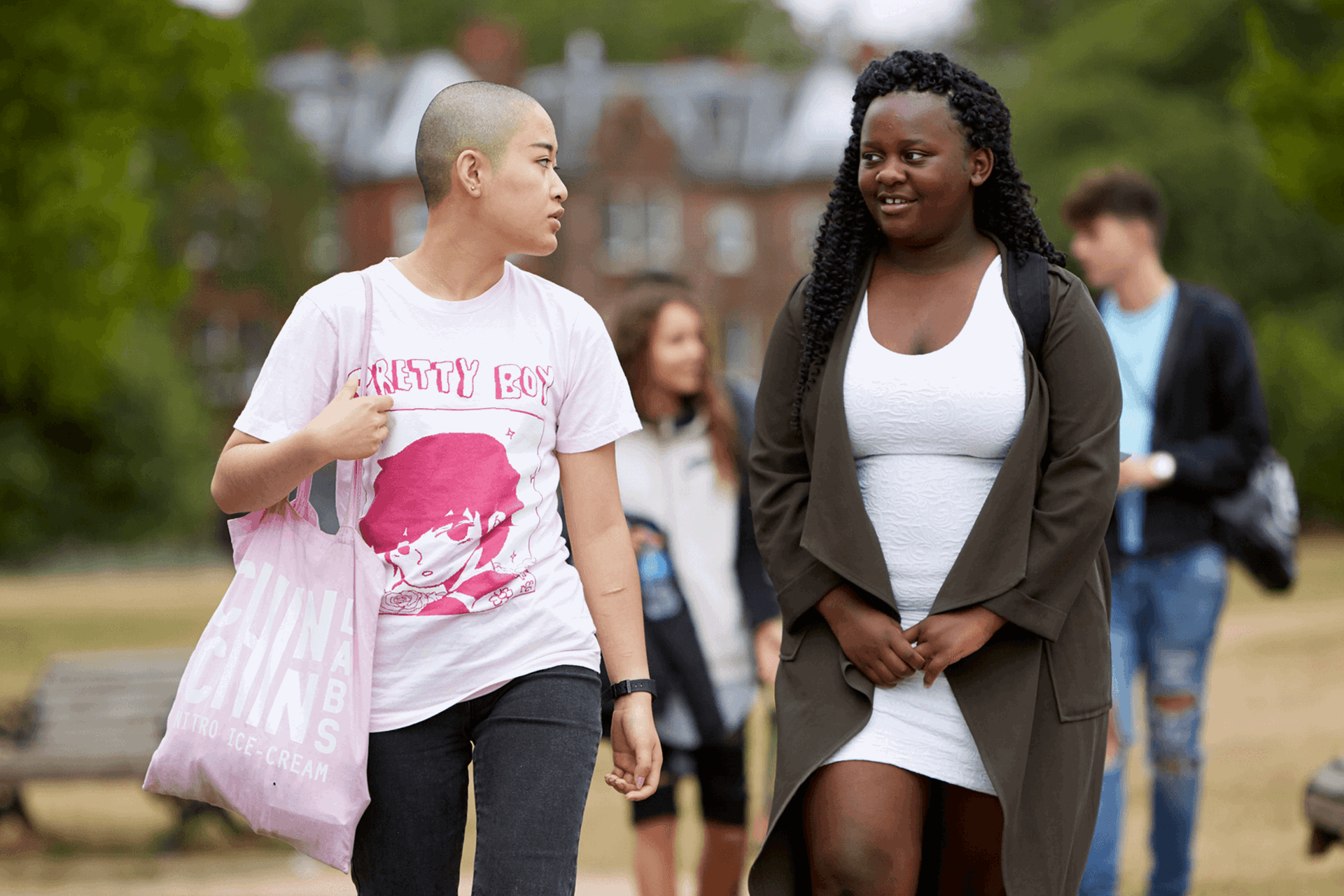 Two young people walking together through a park.