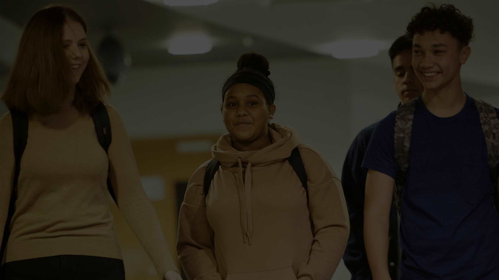 Three students walking in a school corridor smiling