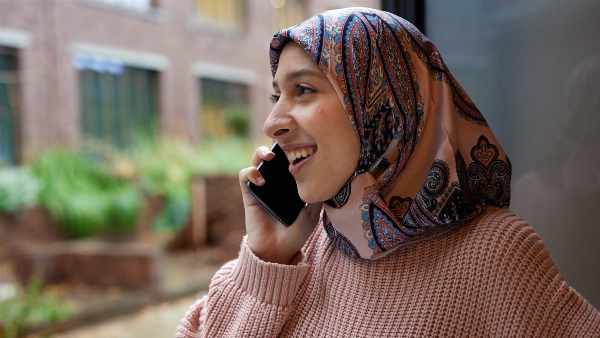 A person wearing a headscarf on the phone.