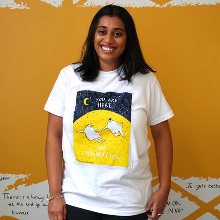A woman smiling wearing a yellow bespoke Rubyetc t-shirt