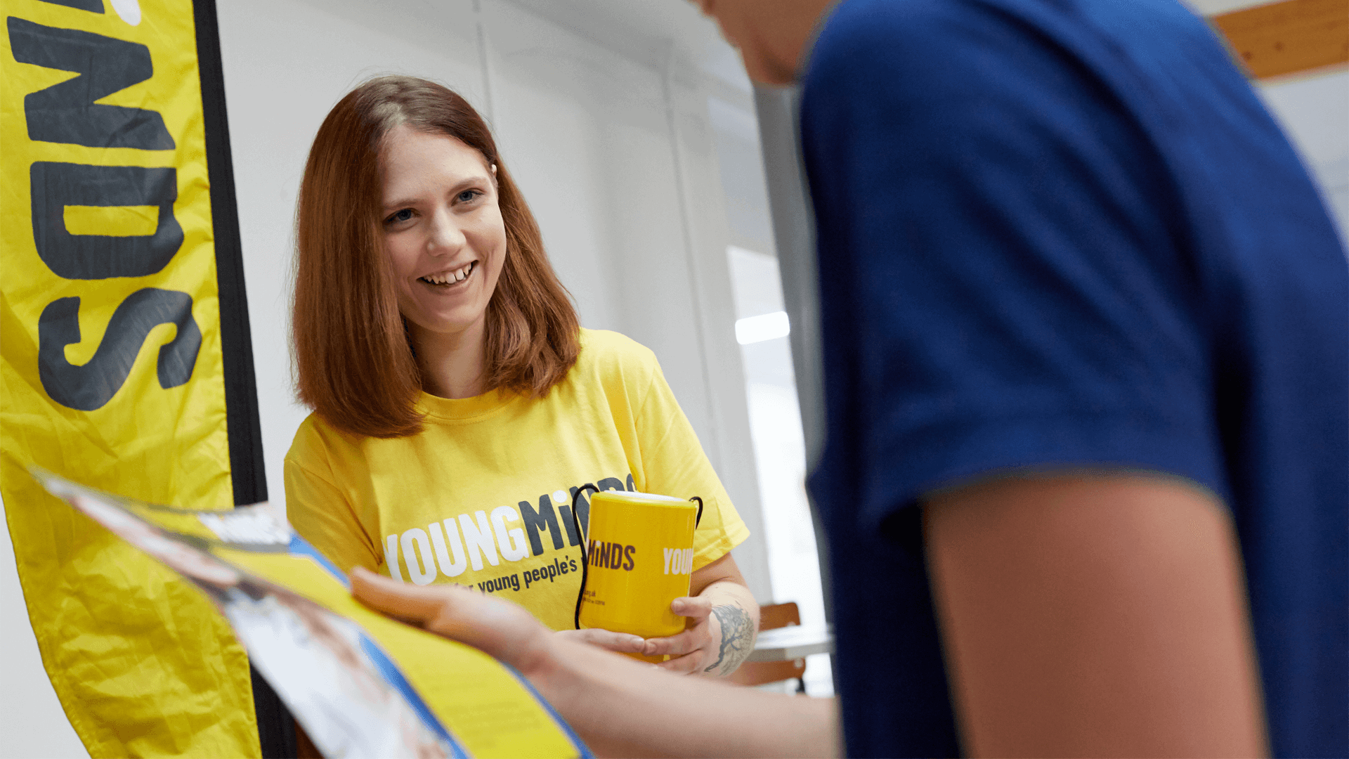 a YoungMinds volunteer wearing yellow YoungMinds shirt smiling in a fundraising event