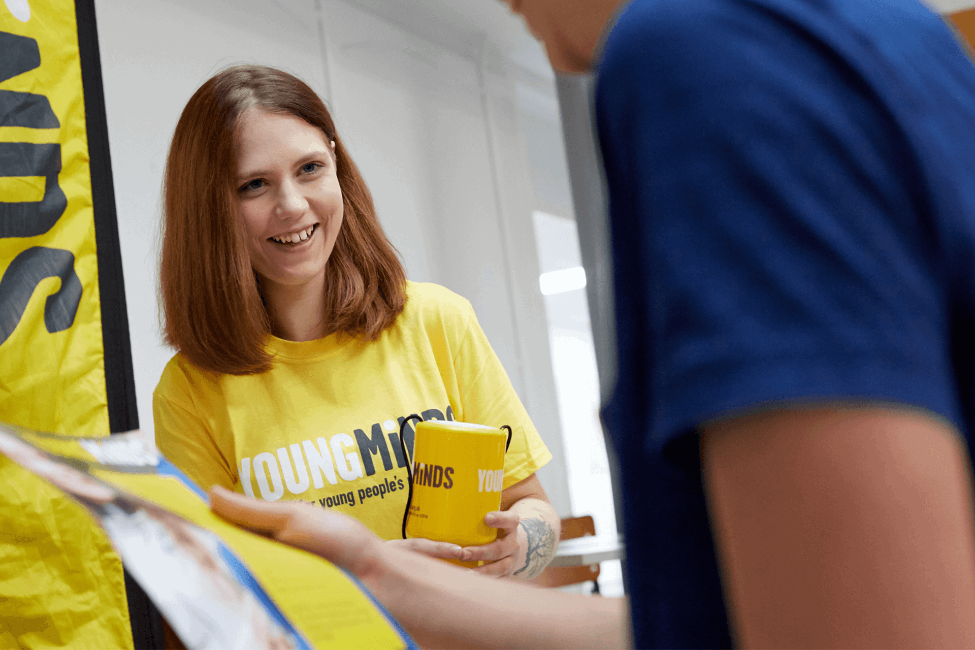 a YoungMinds volunteer wearing yellow YoungMinds shirt smiling in a fundraising event