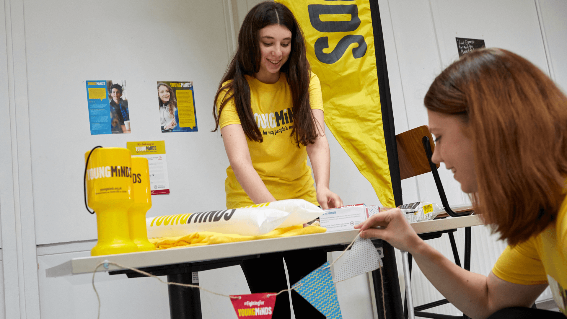 two girl volunteers are tidying up YoungMinds fundraising materials