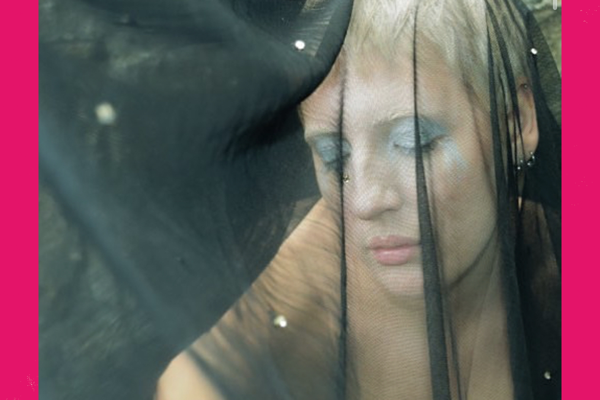 An image of a person in a black veil wearing blue eye makeup.