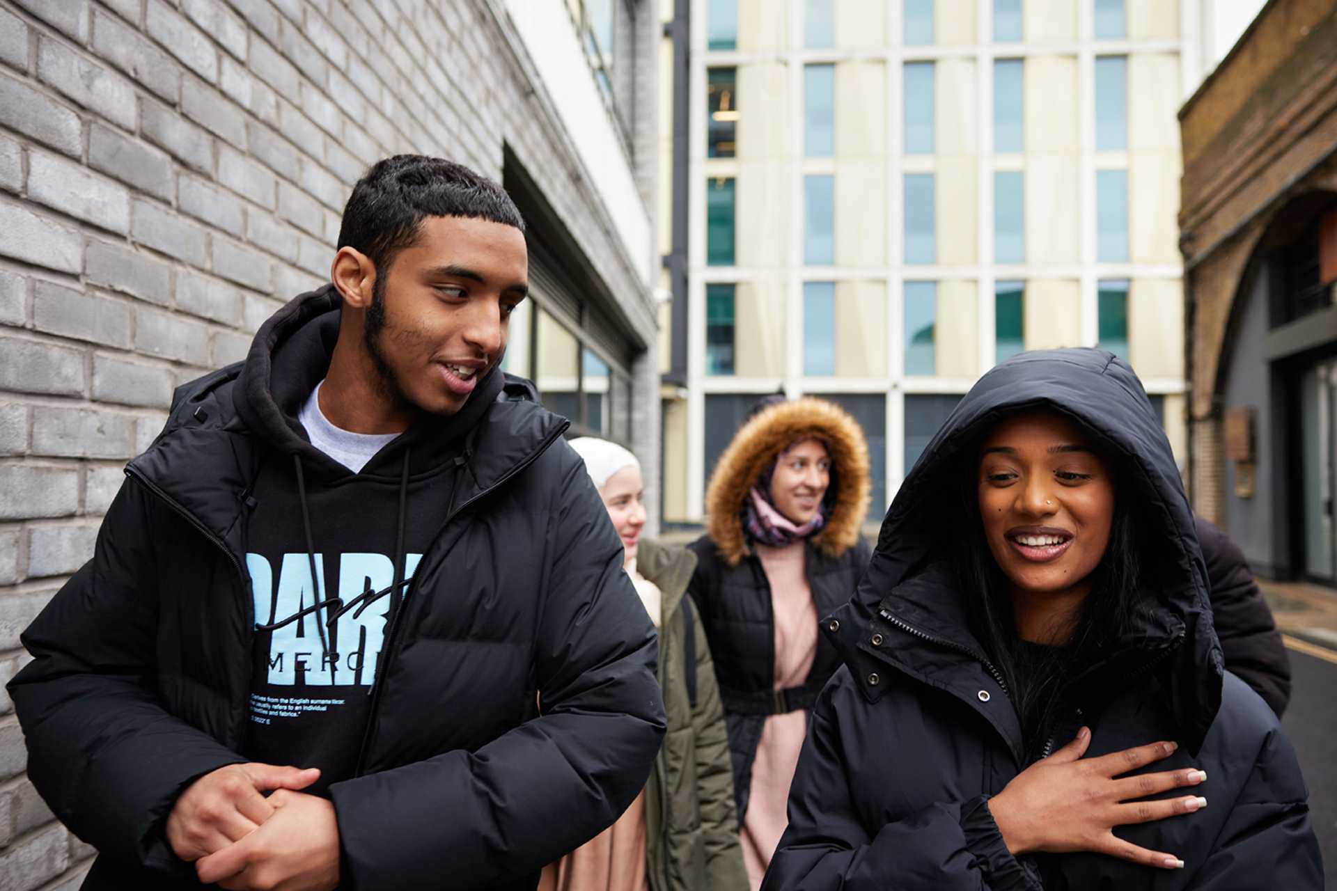 A group of young people walking on the street and talking.
