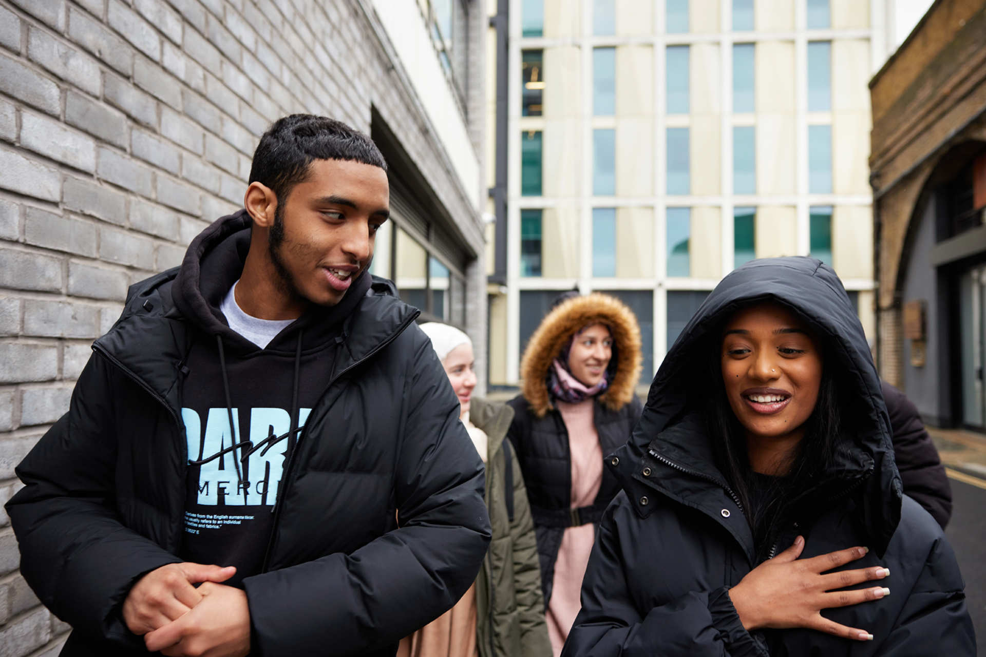 A group of young people walking on the street and talking.