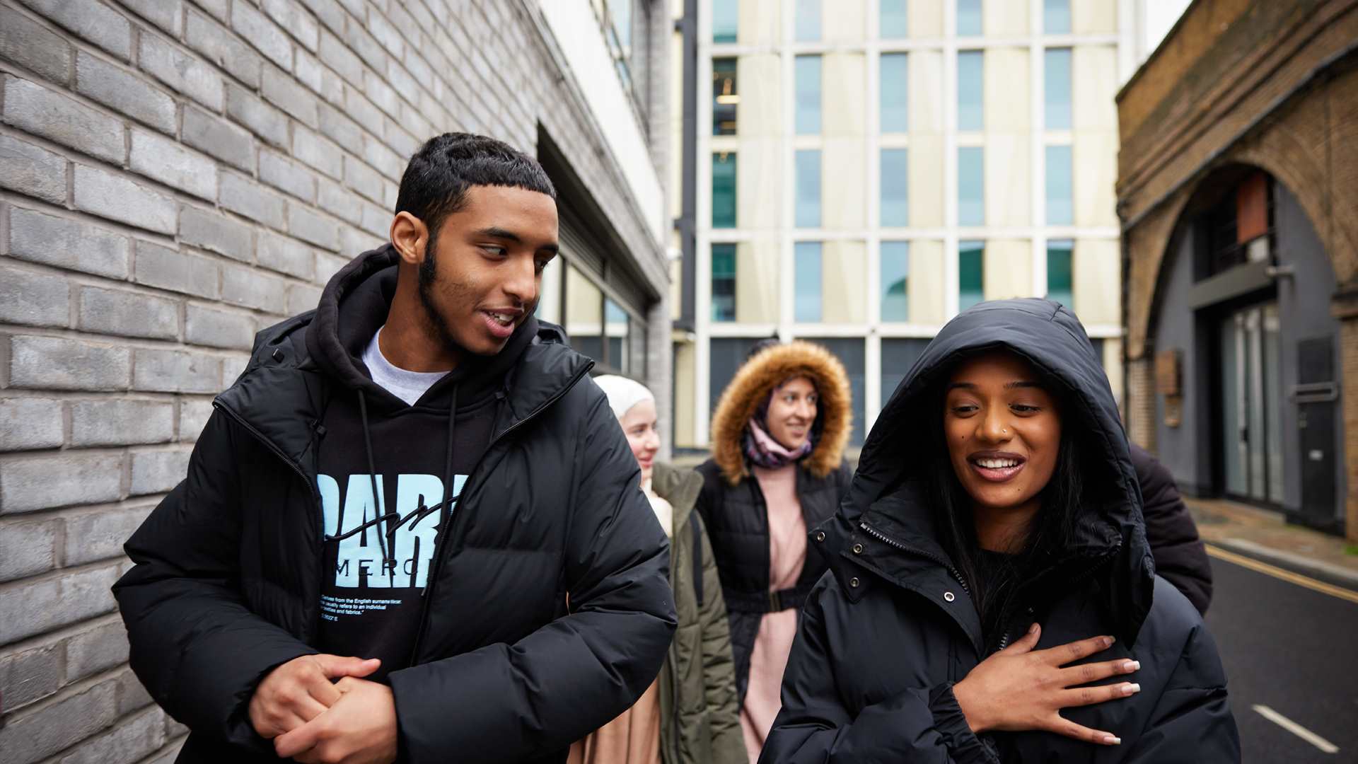 A group of young people walking on the street and talking.