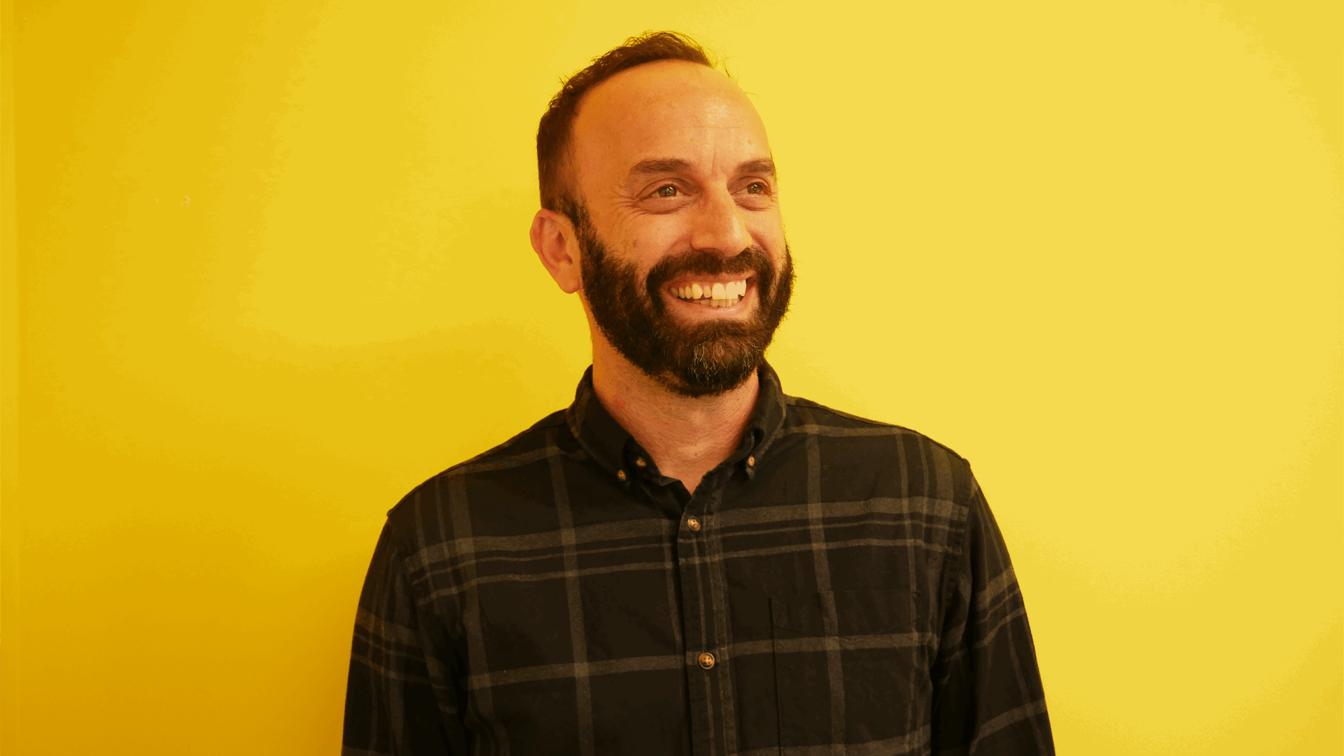 YoungMinds staff member Mike Woolf smiling and against a yellow background