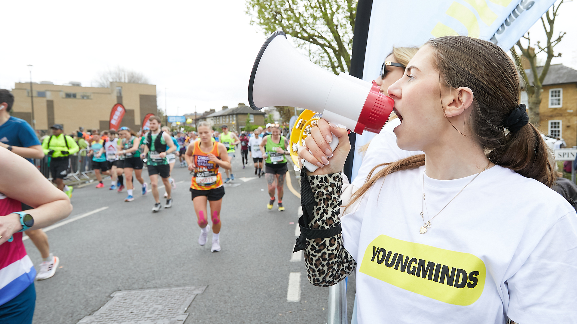 A YoungMinds marathon runner being supported by YoungMinds staff on the side line.