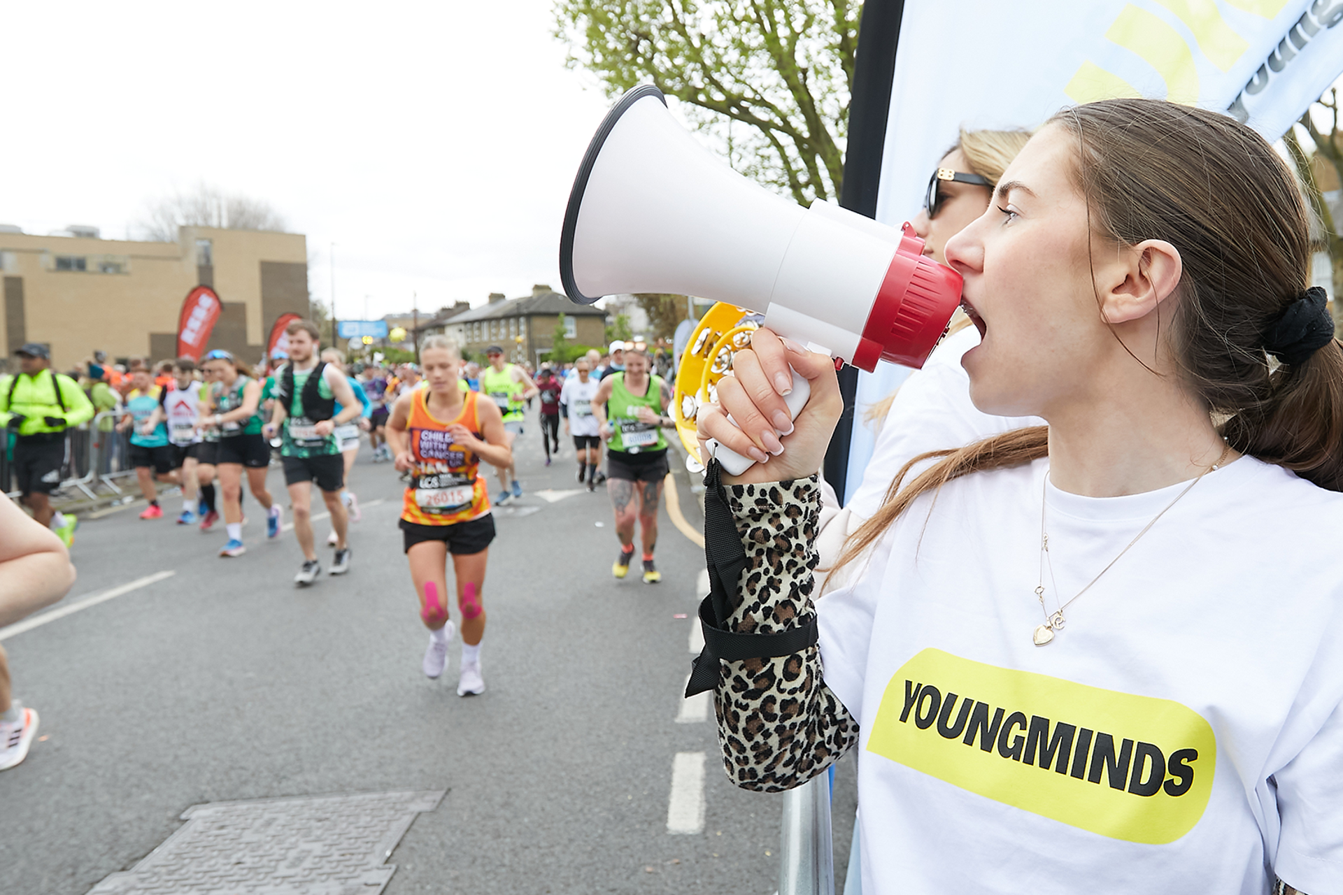 A YoungMinds marathon runner being supported by YoungMinds staff on the side line.