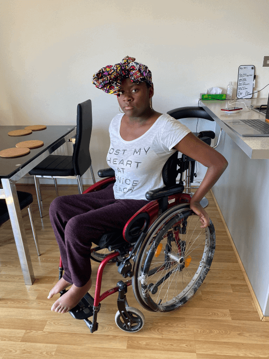Simi in her wheelchair wearing a colourful headwrap.