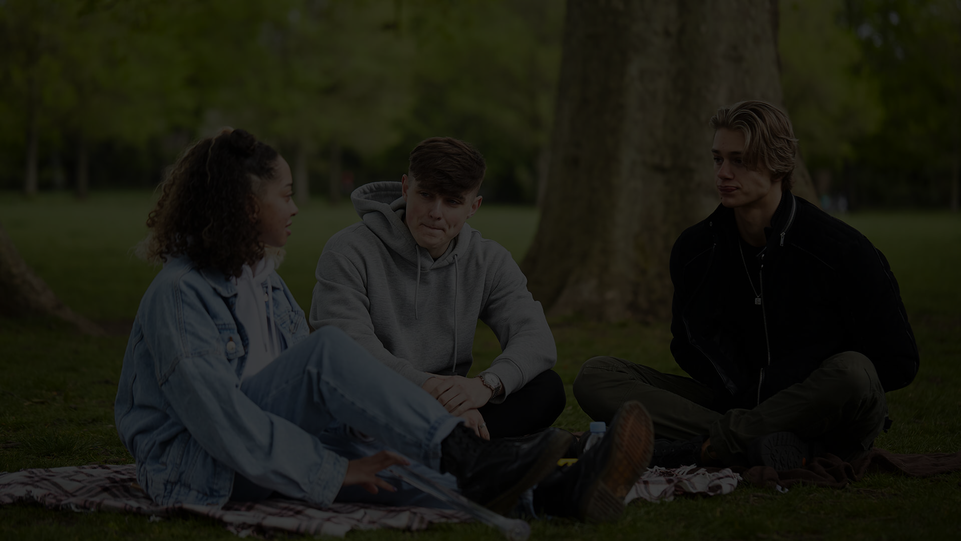 Three young people talking in the park.