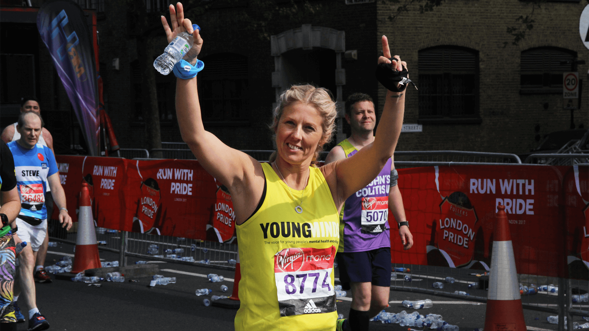 a woman runner and supporter of YoungMinds smile and wave at the camera during a running event