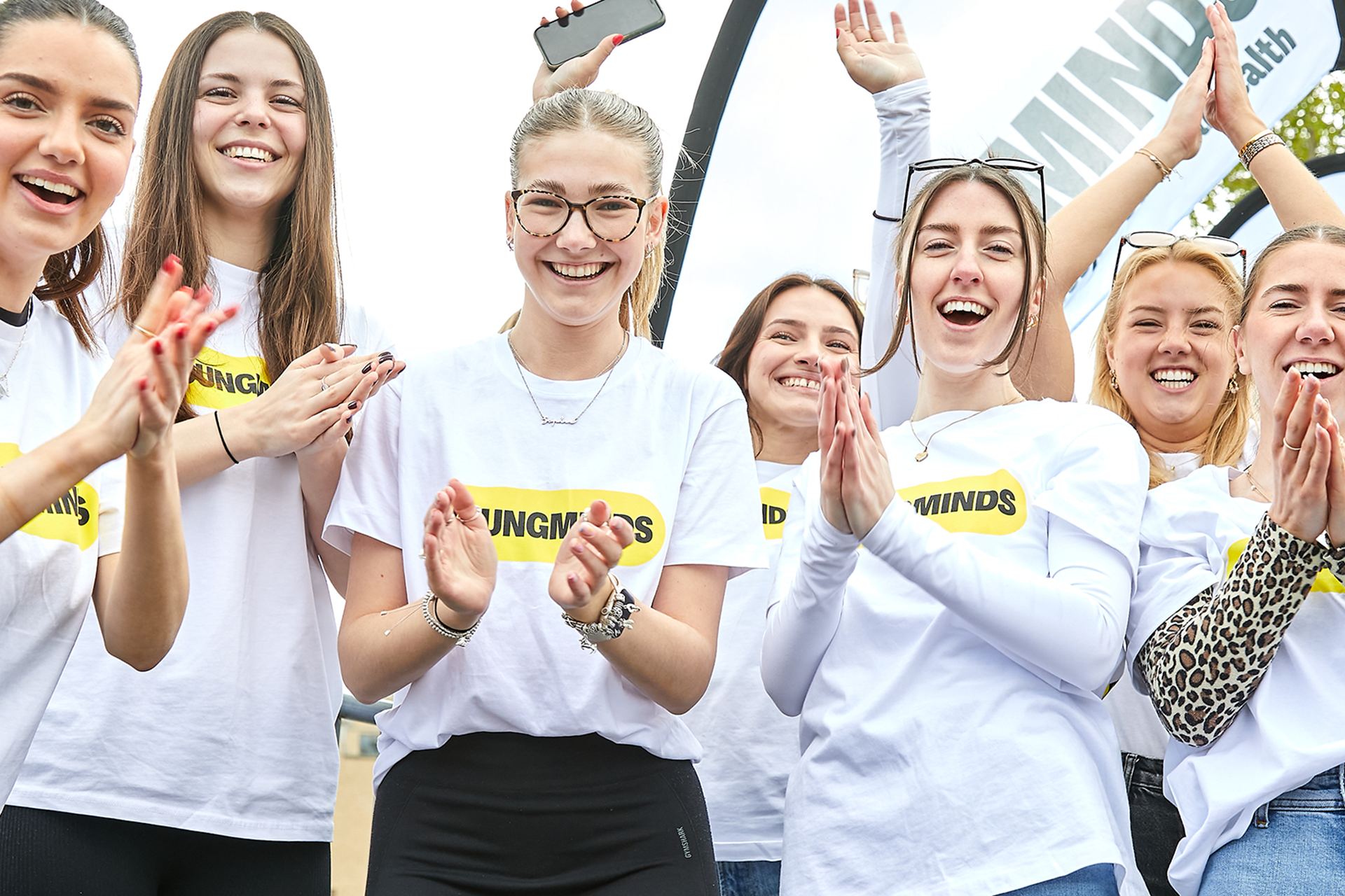 YoungMinds staff cheering marathon runners on from the side line in YoungMinds t-shirts and with YoungMinds banners.