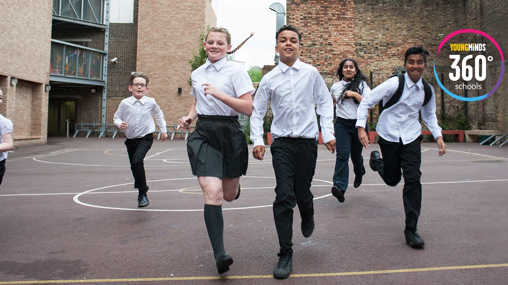 A group of pupils running in the playground with YoungMinds 360 logo