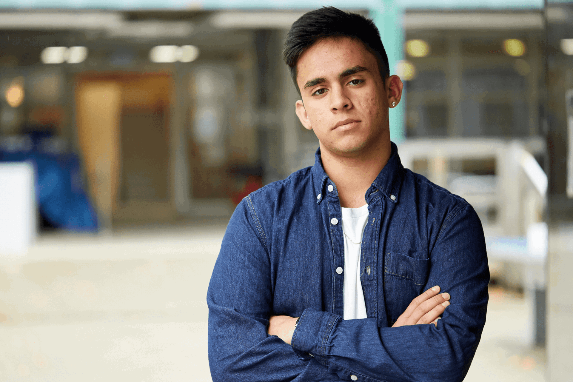 medium-shot-of-a-young-man-looking-in-front-of-the-camera-with-arms-crossed-and-school-campus-on-the-background