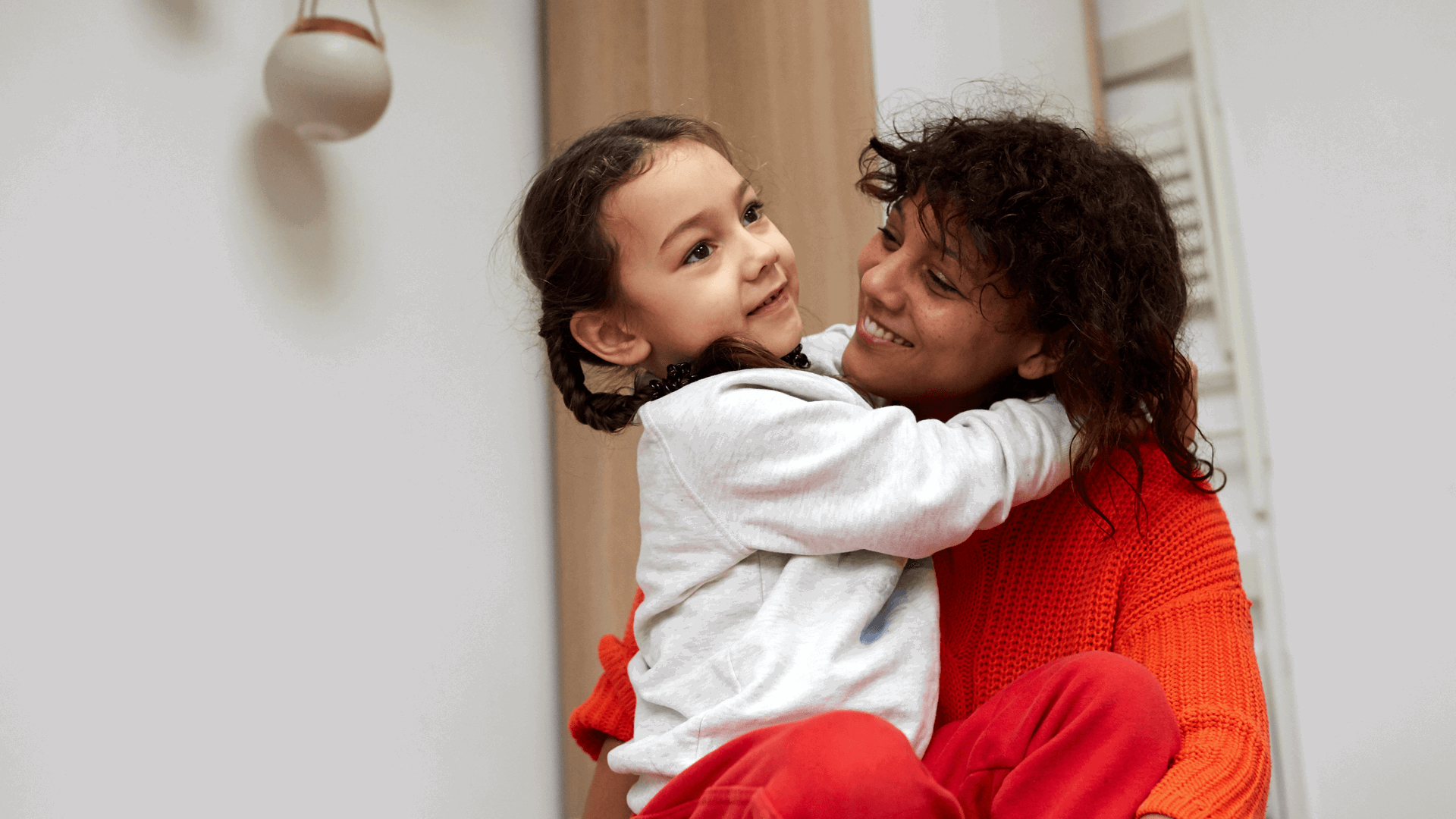 A mother holding her young daughter and smiling