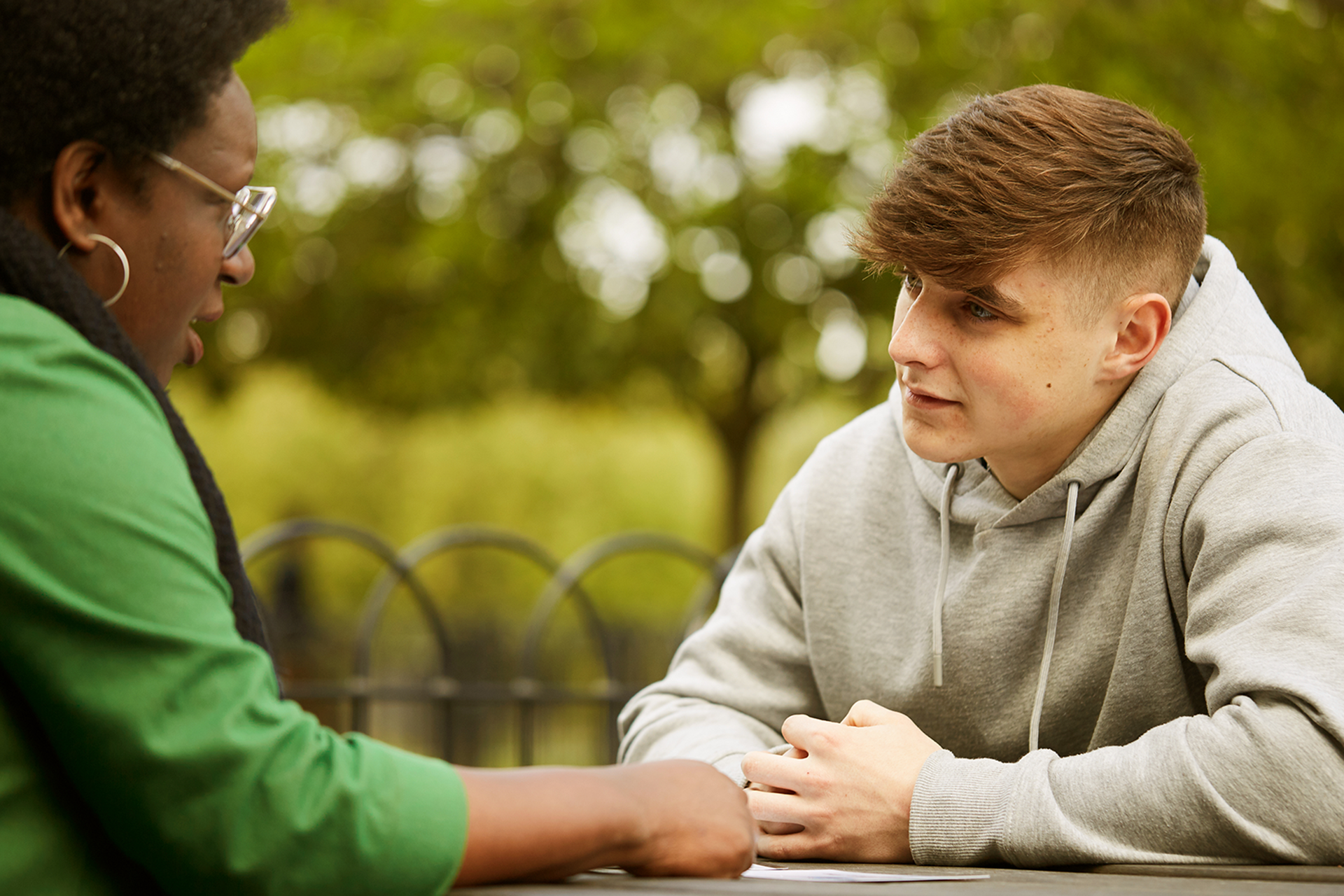 A young person talking to a trusted adult outside on a bench.