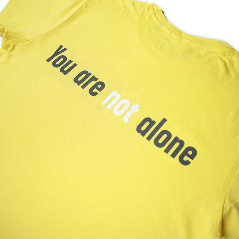 close up of the back of YoungMinds yellow tshirt with You are not alone text graphics