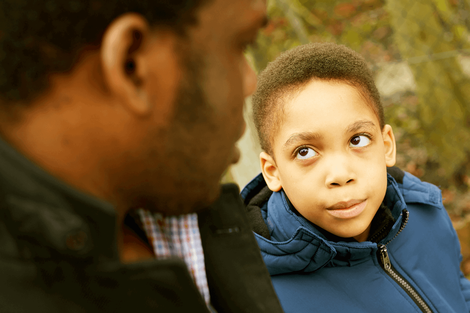 A child sat next to his father and looking up to him.