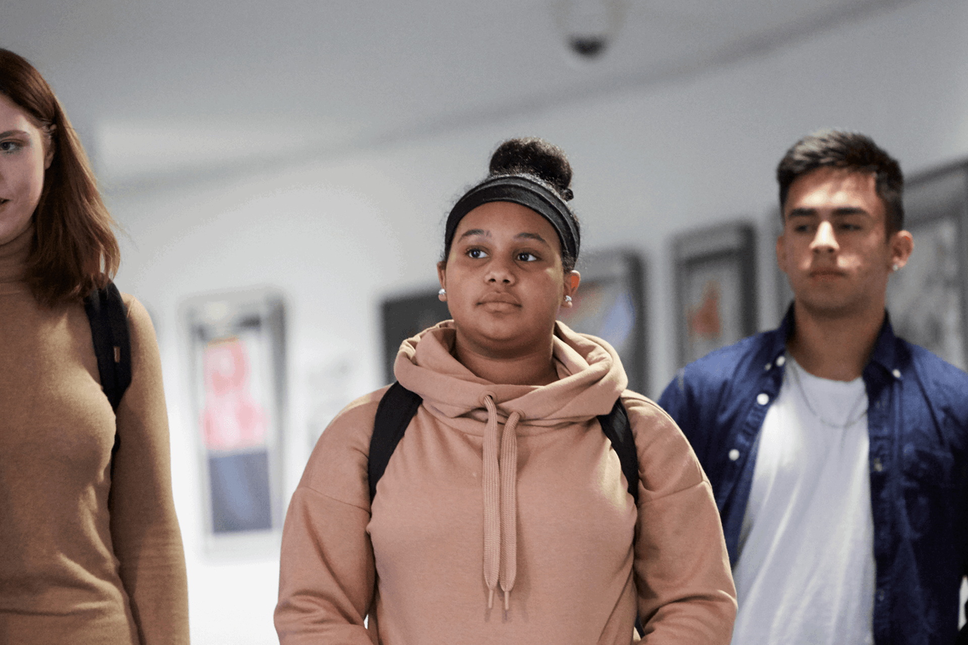 Three students walking down a school corridor.