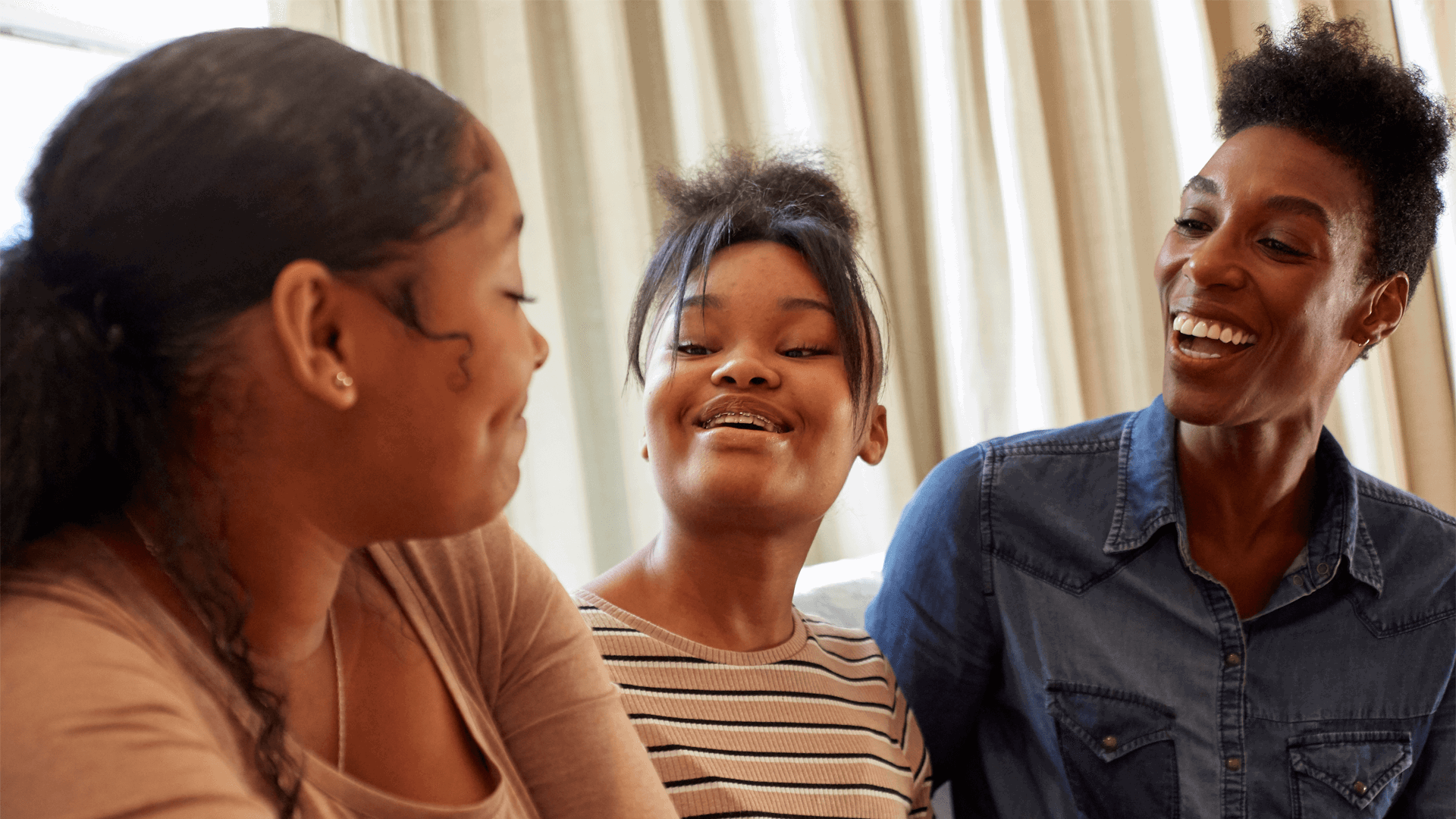 A mother and her two daughters smiling and laughing together.