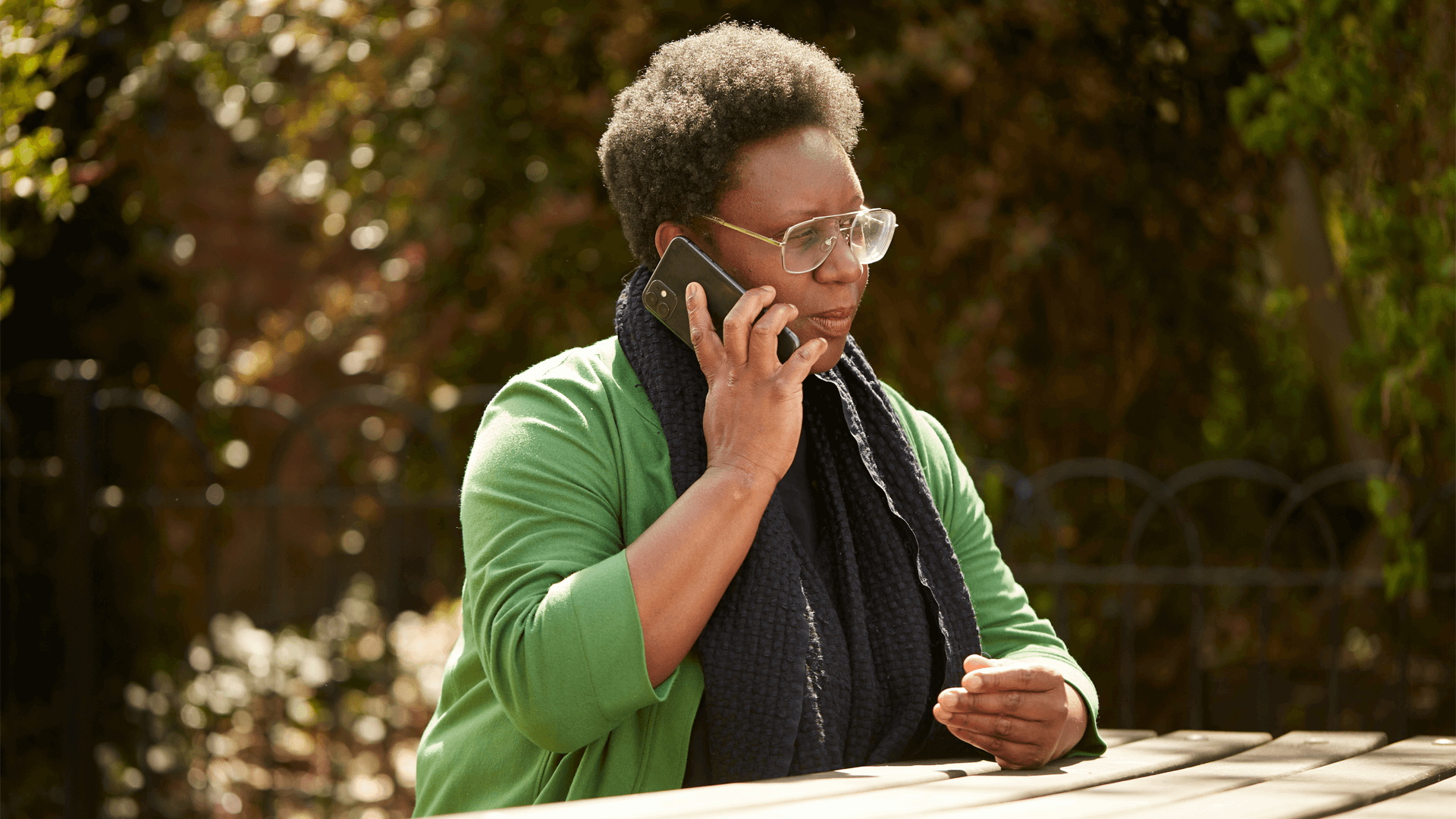 A lady speaking on her mobile phone at a picnic table