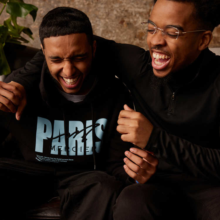 Two people sat on a sofa laughing together.