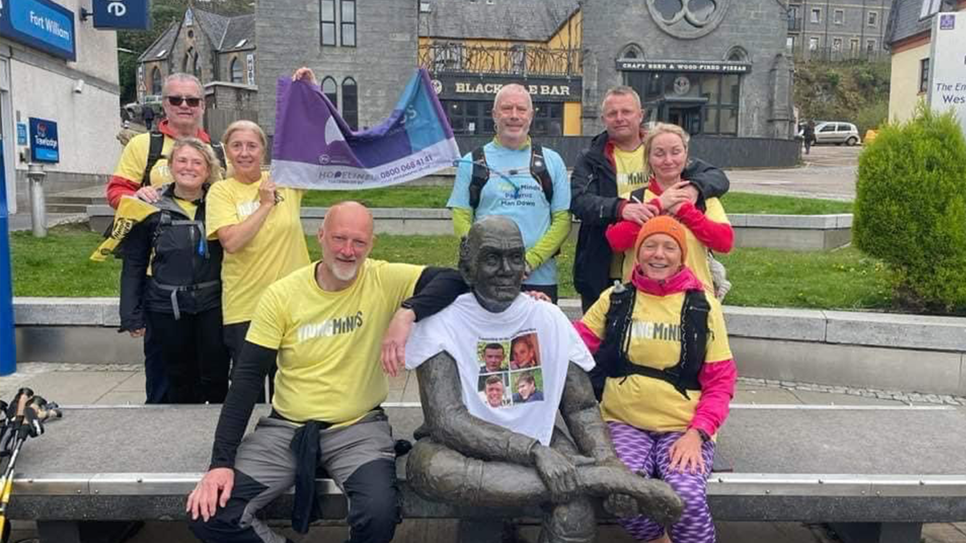 A group picture of 4 Families Walking standing around a statue.