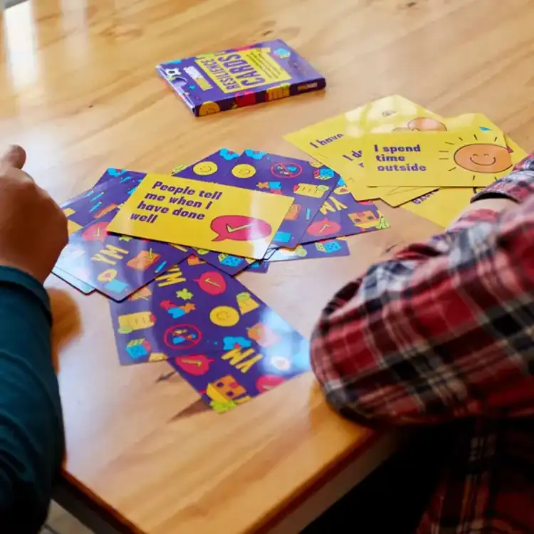 A closeup of hands playing with YoungMinds resilience cards primary pack at the table.